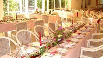 Un salón de banquetes con largas mesas dispuestas para un evento formal, con centros de mesa florales y elegantes vajillas.