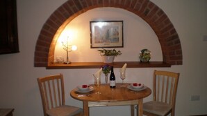 A dining area with a brick arch, a table set with plates, wine, and flowers, and two chairs. - Farmhouse Cottage Sleeps 2 (1 en-suite Bedroom) (Congleton)