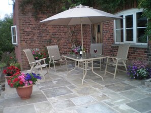 Relax in the serene patio area with a table for four, umbrella, and lush greenery.