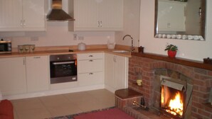 A kitchen with white cabinets, a built-in oven, a microwave, a sink, and a brick fireplace. - Farmhouse Cottage Sleeps 2 (1 en-suite Bedroom) (Congleton)
