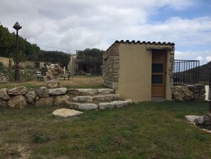 A small stone building with a wooden door, surrounded by a stone wall and steps leading up to it.