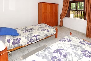 A bedroom with a bed, a wooden wardrobe, and a window with curtains.