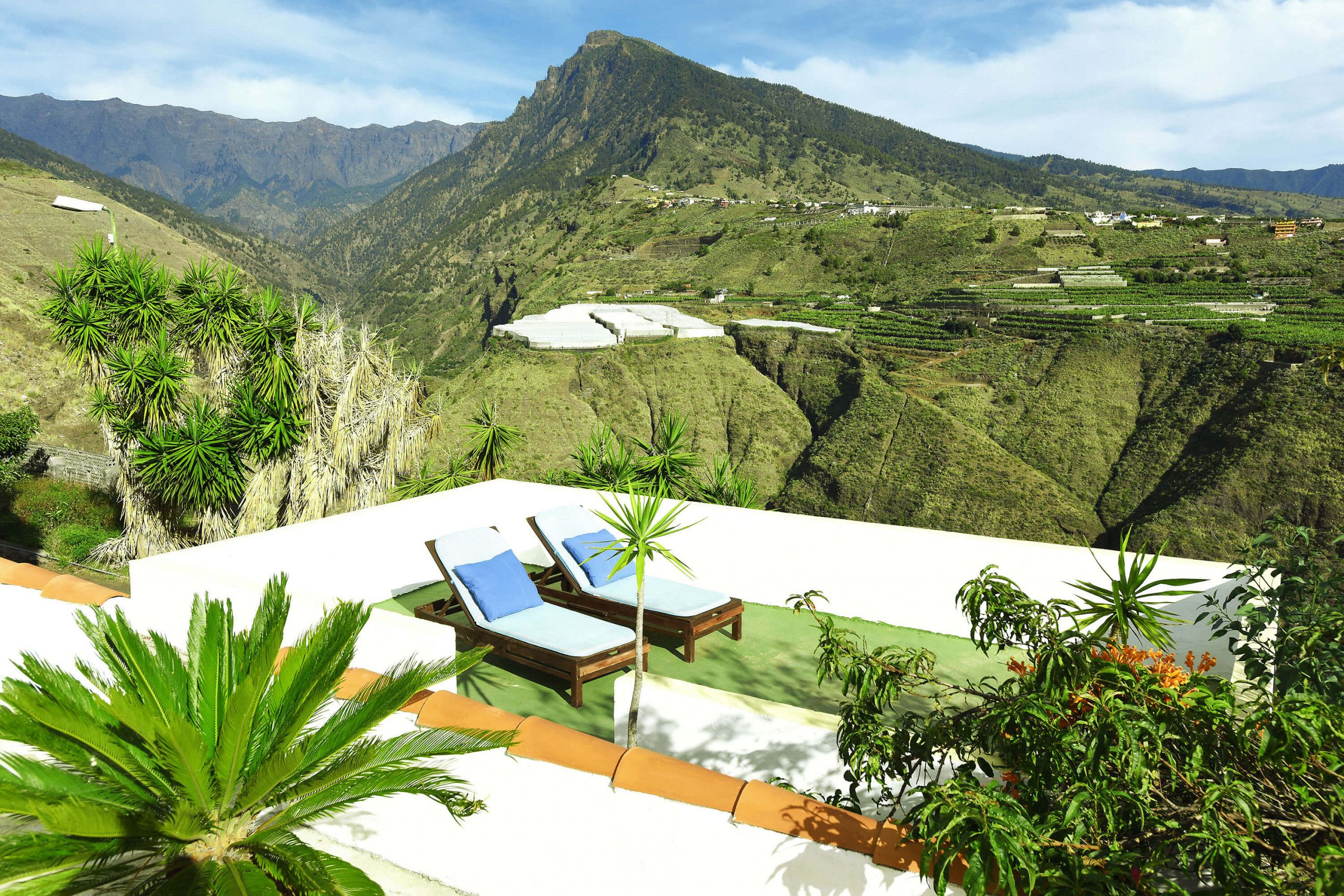 A resort with a pool area, lounge chairs, and a view of a mountainous landscape.