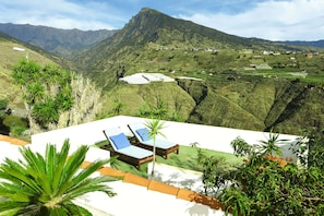 Un complexe hôtelier doté d’une piscine, de chaises longues et offrant une vue sur un paysage montagneux.