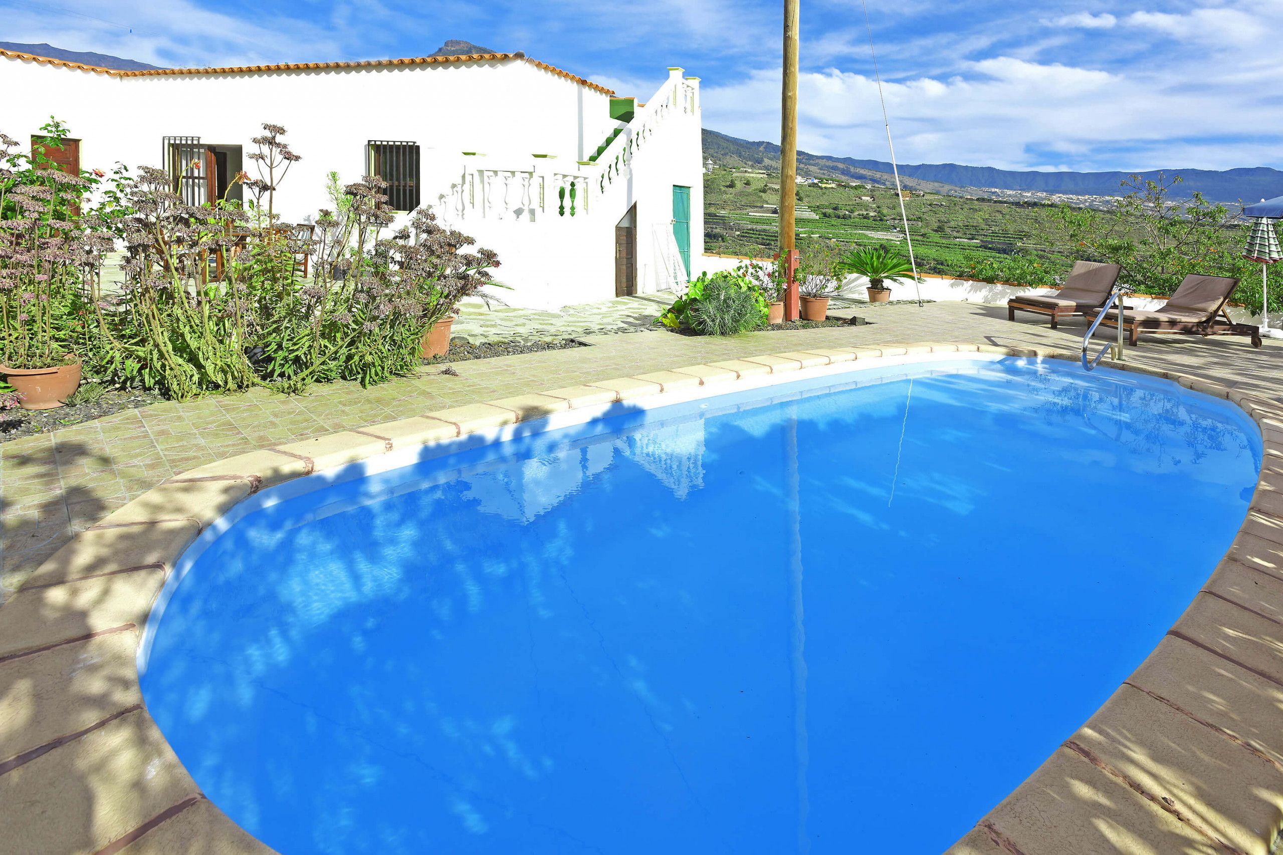 A swimming pool with a view of a white building and mountains in the background.