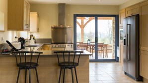 Una cocina moderna con una isla central, taburetes de bar, horno empotrado y refrigerador.