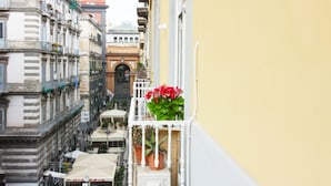 A narrow street with buildings on either side, a visible restaurant, and a balcony with potted plants. - Le Quinte del Bellini (Naples)