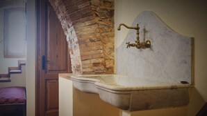 A bathroom with a marble sink, a brick wall, and a wooden door. - Villa with private pool, 5 minutes drive from the beach of Forte dei Marmi. (Ripa di Seravezza Lucca)