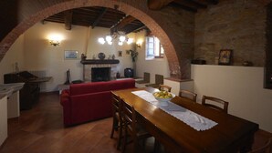 A rustic dining area with a wooden table, red sofa, and a fireplace. - Villa with private pool, 5 minutes drive from the beach of Forte dei Marmi. (Ripa di Seravezza Lucca)