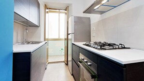 A modern kitchen with a gas stove, stainless steel appliances, and a view to the outside. - Casa dell'Artista Roma (Rome)