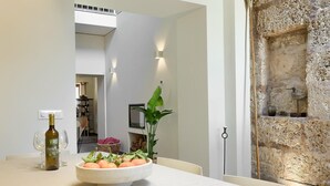 A dining area with a table set for two, a bottle of wine, a bowl of fruit, and a potted plant. - Stylish townhouse with large pool, central Pollensa (Pollensa / Pollença)