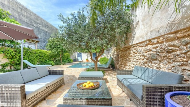 A sunlit outdoor seating area with wicker furniture and a pool. - Stylish townhouse with large pool, central Pollensa (Pollensa / Pollença)