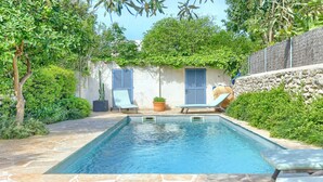 A rectangular pool with two lounge chairs and a potted plant, surrounded by greenery and a stone wall. - Stylish townhouse with large pool, central Pollensa (Pollensa / Pollença)