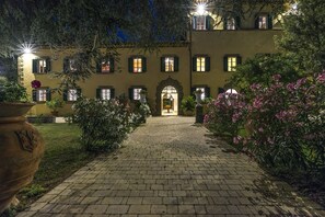 A courtyard with a paved walkway leading to a building with multiple windows and a central archway.