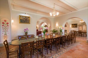 A dining area with a round table, wooden chairs, and floral centerpieces.