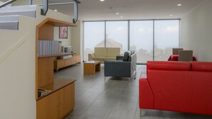 A modern living room with a staircase, a red sofa, a beige sofa, and a wooden cabinet with books. - A Casa do Lagar In a peaceful and solitary area with a pleasant climate all year (São Jorge)
