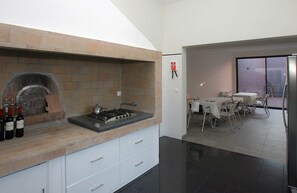 Una cocina con horno empotrado y un comedor con mesas y sillas.