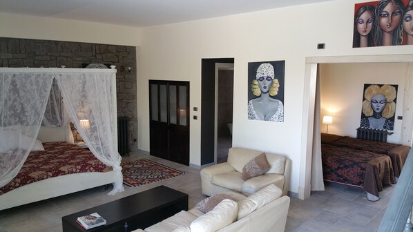 A bedroom with a four-poster bed, a sofa, a coffee table, and two paintings on the wall. - VILLA MOSè Apartment pool, garden, parking (CIR: 19084001C100589) (AGRIGENTO)