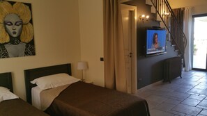 A hotel room with two beds, a television on the wall, a staircase, and a door leading to another room. - VILLA MOSè Apartment pool, garden, parking (CIR: 19084001C100589) (AGRIGENTO)
