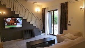 A living room with a staircase, a television, a radiator, and a sofa.