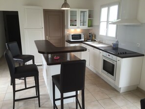Kitchen features a central island with a sink, stove, microwave, and white cabinetry.