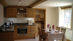 Une cuisine avec des meubles de rangement en bois, un four encastré et une table à manger avec des chaises.