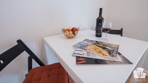 Een eettafel met een fles wijn, een glas en een schaal fruit.