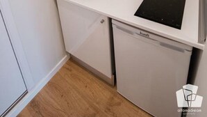 Een kleine keuken met een magnetron, spoelbak en een geïntegreerde vaatwasser.