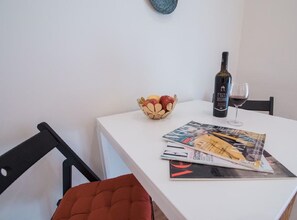 Una mesa de comedor con una botella de vino, una copa y un bol de fruta.