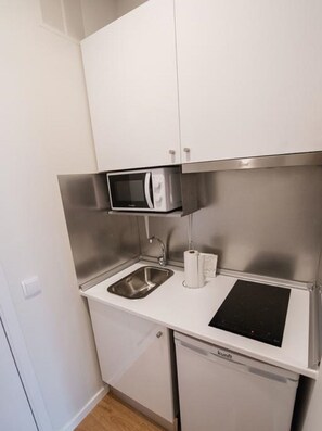 Una kitchenette compacta con microondas, lavabo y lavavajillas integrado.