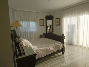 Une chambre à coucher avec un lit en bois, une table de chevet avec une lampe, un miroir et une vue sur un escalier.