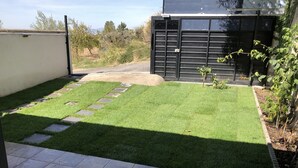 A well-maintained garden with a paved patio area and a black gate. - Adonay's house, it's also your house! (Huétor Vega)