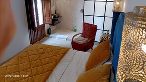 A hotel room with a bed, a red chair, a small bathroom, and decorative wall panels. - Adonay's house, it's also your house! (Huétor Vega)