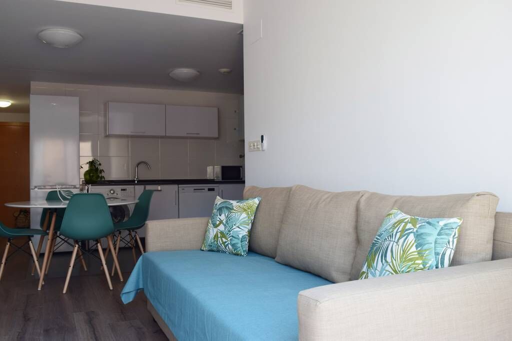 Un salon moderne avec un canapé beige, des coussins turquoise et une nappe bleue.