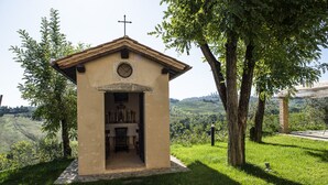 A small chapel with a cross on top, surrounded by trees and a grassy area. - Martina, apartment with terrace on the green hills of San Giminiano (San Gimignano)