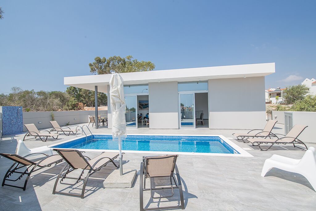 A modern pool area with lounge chairs and a building with large windows.