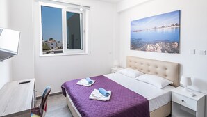 A modern bedroom with a bed, a desk, and a window with a cityscape view. - Villa Desi, Luxury and new 5BDR Protaras Villa with pool and stunning sea views (Protaras)