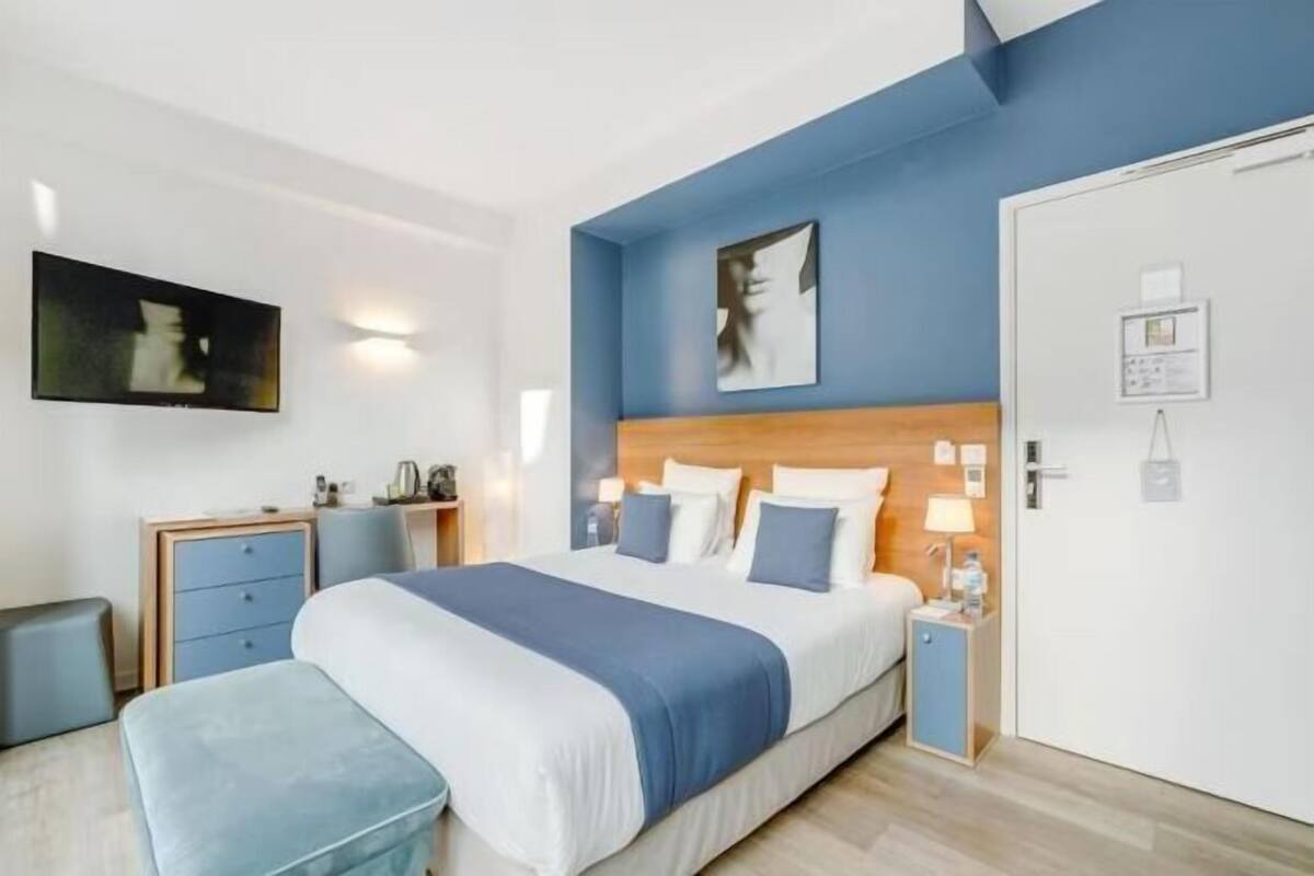 Een slaapkamer met een bed, nachtkastjes, een kledingkast en een aan de muur bevestigd schilderij.