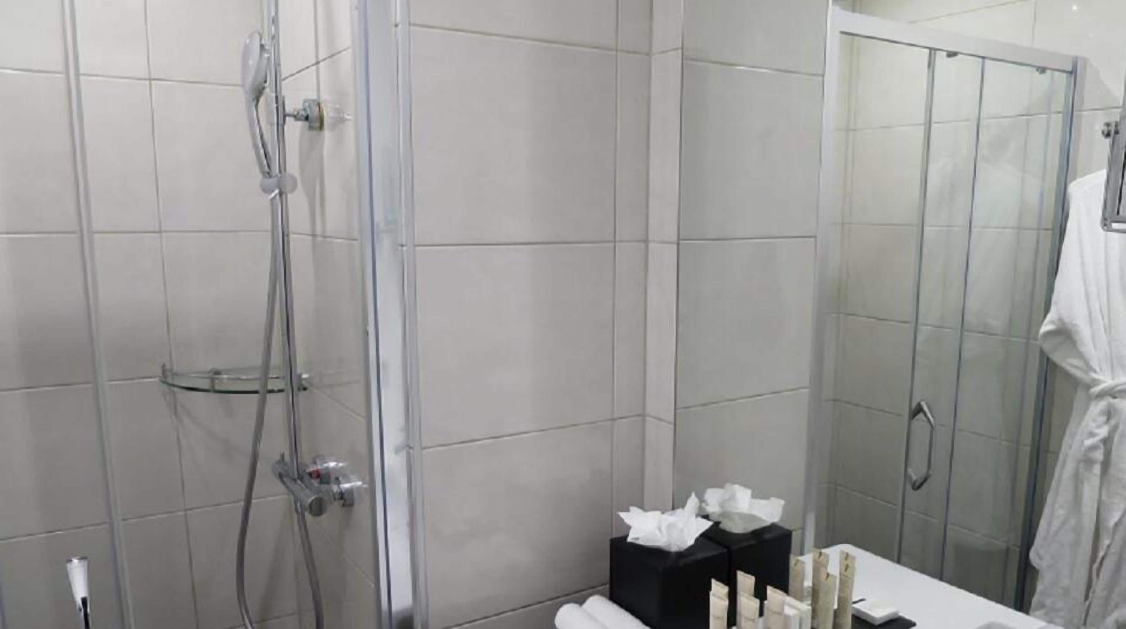 Un bagno moderno con doccia vetrata, piastrelle bianche e porta asciugamani.