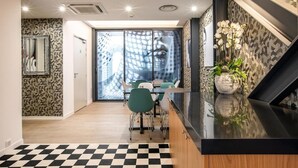 A modern kitchen with a black countertop, a checkered floor, and a dining area with green chairs.