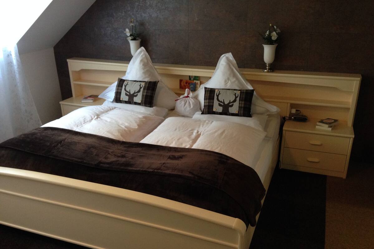 A neatly made bed with white linens and two decorative pillows featuring a deer motif.