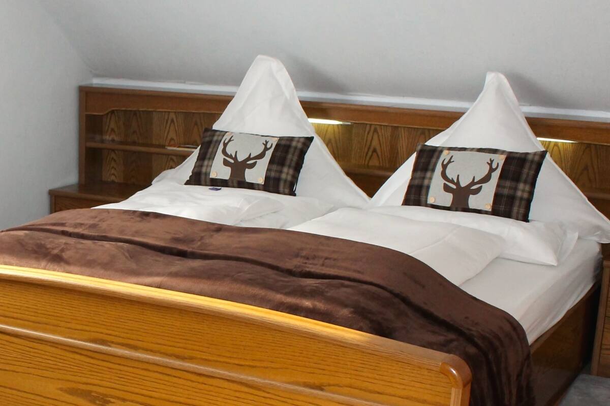 A bed with a brown headboard and two pillows with deer silhouettes.