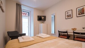 A hotel room with a large bed, a desk with a chair, a television, and framed pictures on the wall. - Alfama Dream Apartments 1 (Lisboa)