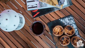 A table with a magazine, a teapot, a cup of tea, and pastries. - Alfama Dream Apartments 1 (Lisboa)
