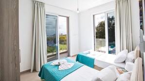 Habitación de hotel con dos camas, un balcón y vistas panorámicas, además de un ventanal grande.
