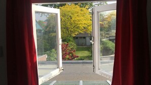 An open door leading to a garden with a yellow tree and a small house. - 300 meters from the sunniest coast of the Netherlands (Vlissingen)