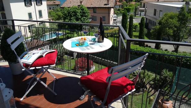 A balcony with a table, chairs, and a view of a lake and mountains.