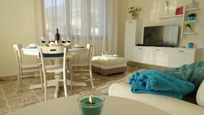 A living room with a dining area, a sofa, a TV, and a fireplace.
