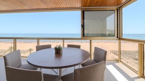 Ein runder Tisch mit sechs Stühlen, einer kleinen Pflanze und Blick auf Strand und Meer.