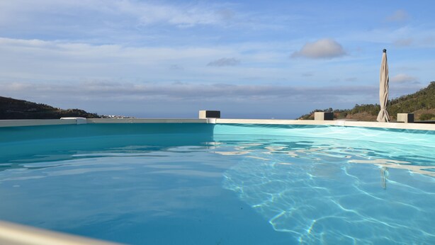 Une piscine d’un bleu éclatant, offrant une vue sur le ciel et les collines lointaines.